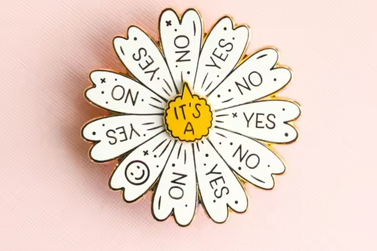 A white flower pin with short words on its petals.