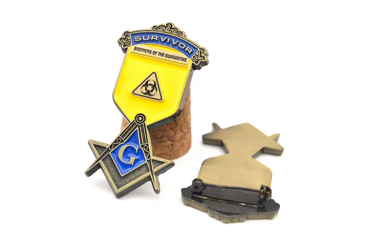 A small group of shaped gold and blue metal pins with a horizontal safety-pin reverse.