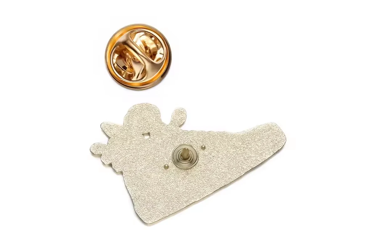 A gold-tone butterfly clutch above the textured back of a shaped pin.