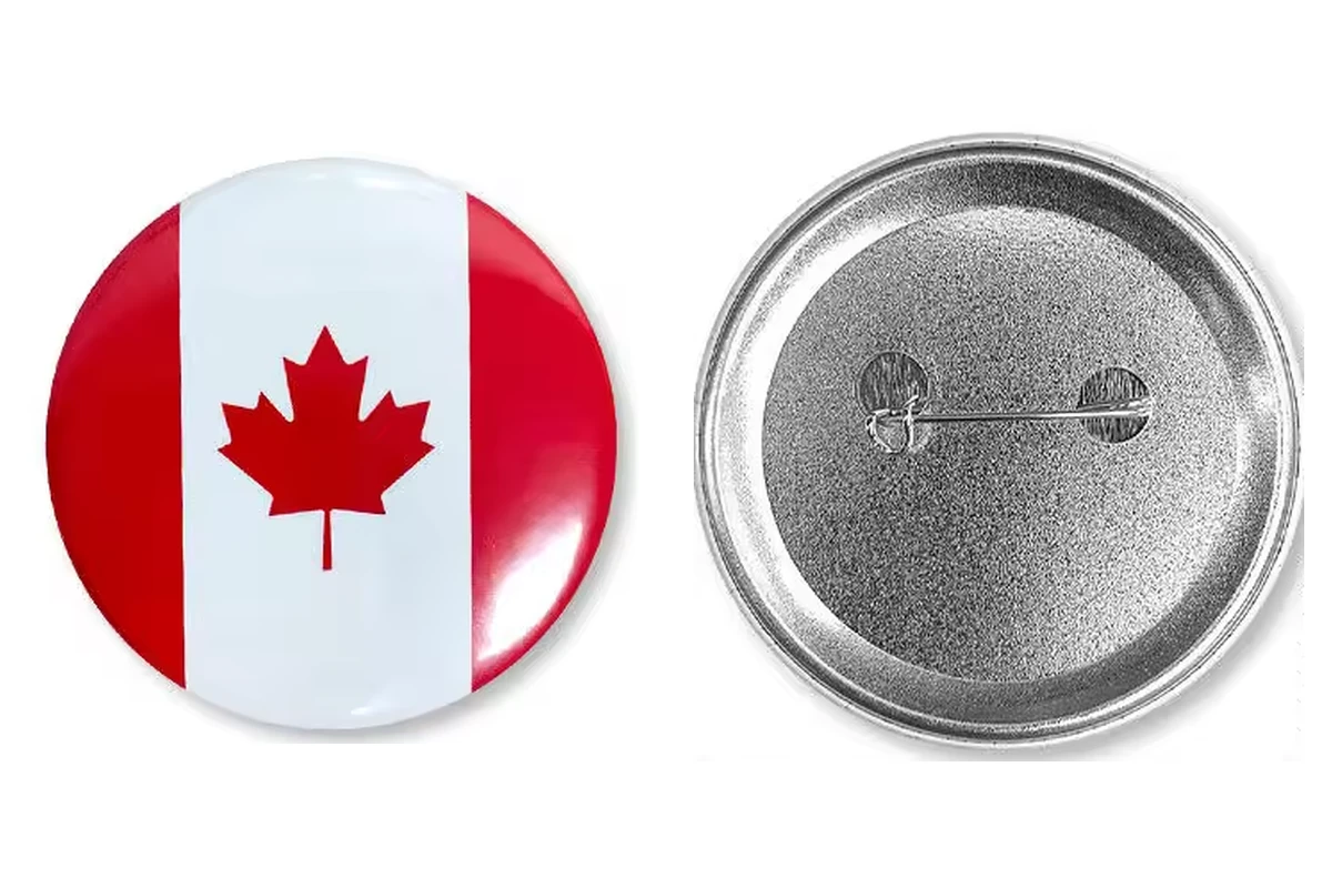 A round Canadian flag button badge beside its silver reverse with a safety-pin closure.