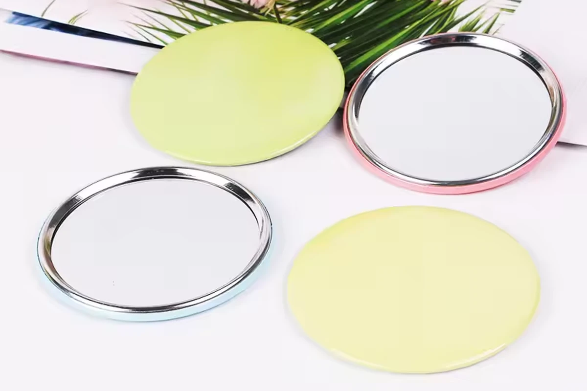 Round silver mirror backs and pale yellow badge faces arranged beside flowers.