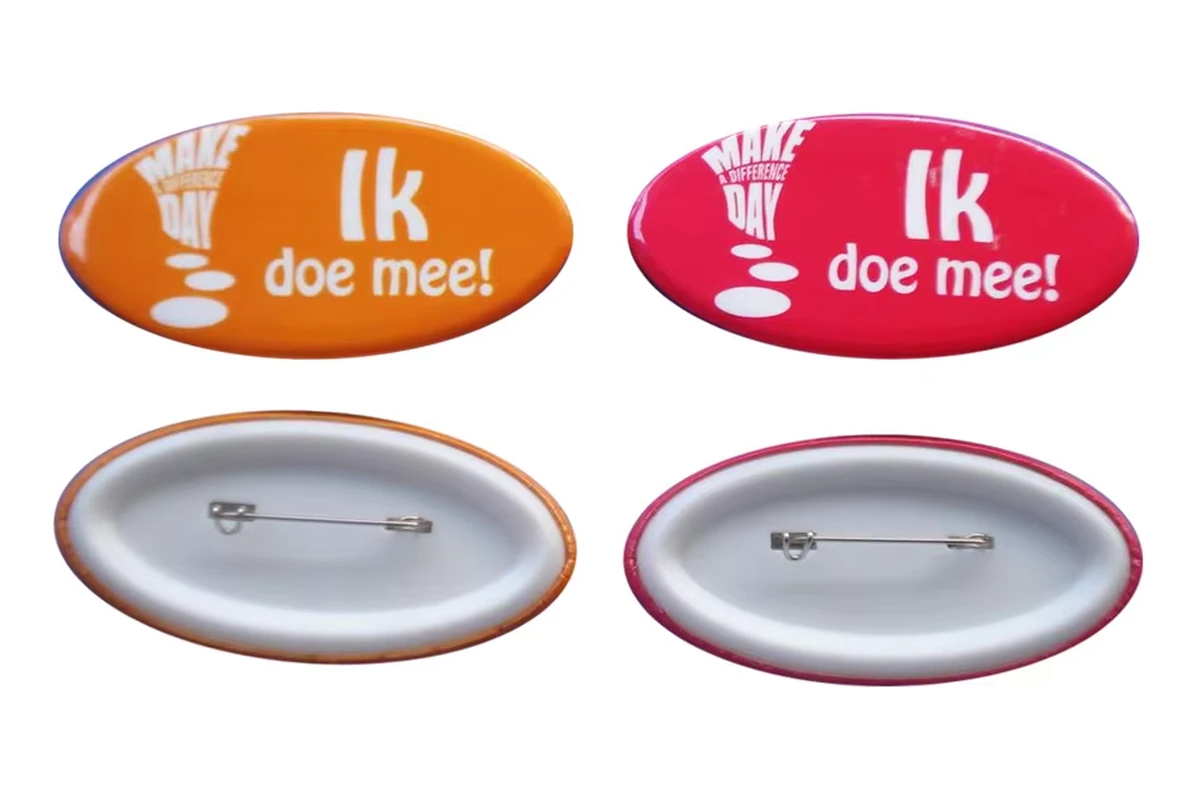 Orange and red oval printed button badges shown with their silver safety-pin backs.