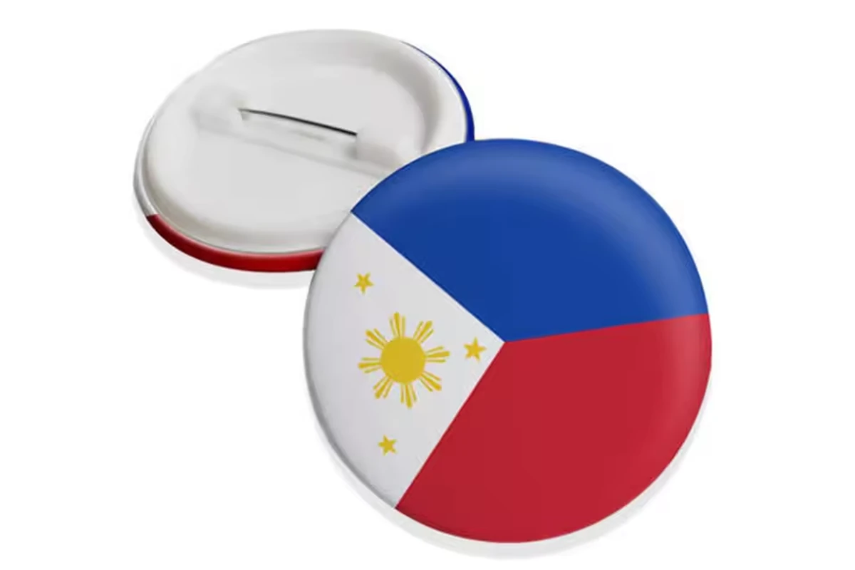 A round Philippine flag button badge beside its reverse with a safety-pin closure.