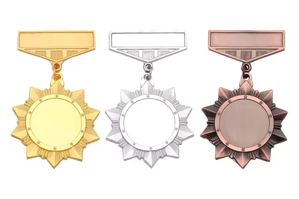 Three sunburst-shaped medal pins in gold, silver and bronze finishes.