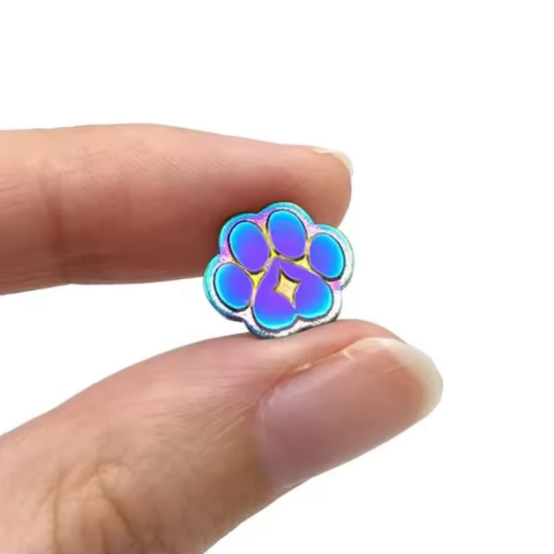A hand holding an iridescent paw pin.