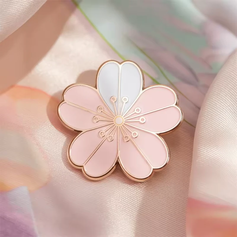 A pale pink blossom pin with gold details.