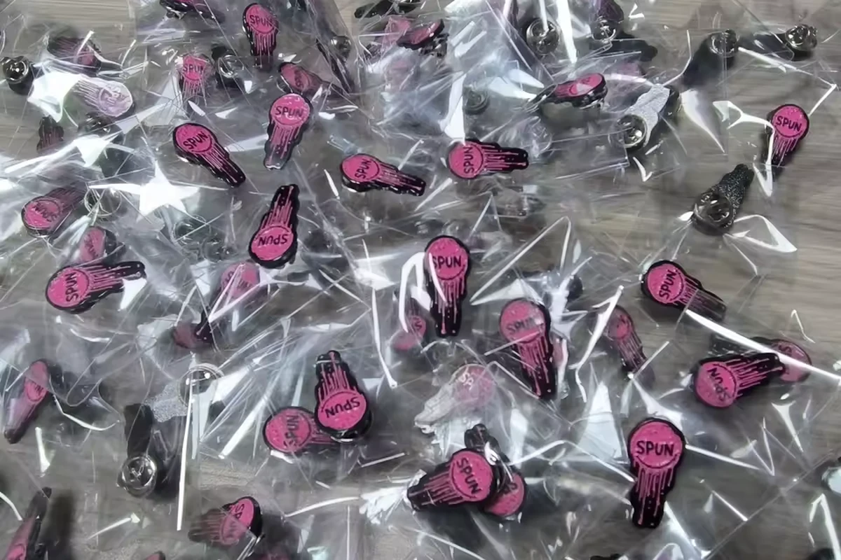 A large batch of pink and black shaped pins packed in separate clear plastic bags.