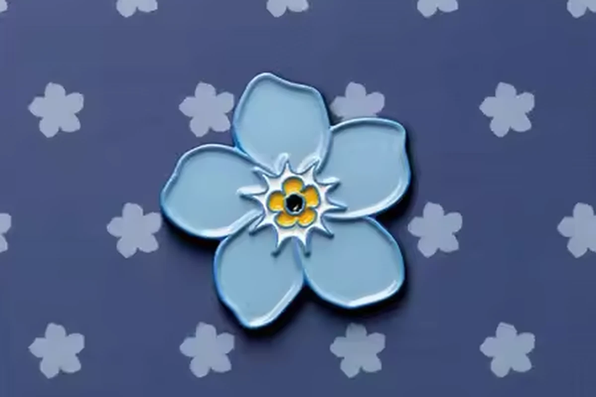 A blue flower pin on a patterned backing card.