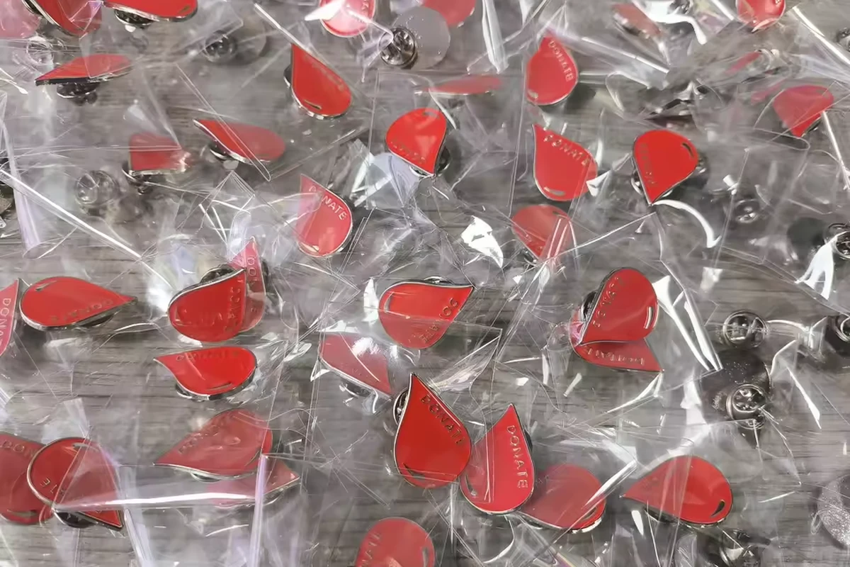 A large batch of red drop-shaped pins individually wrapped in clear plastic bags.