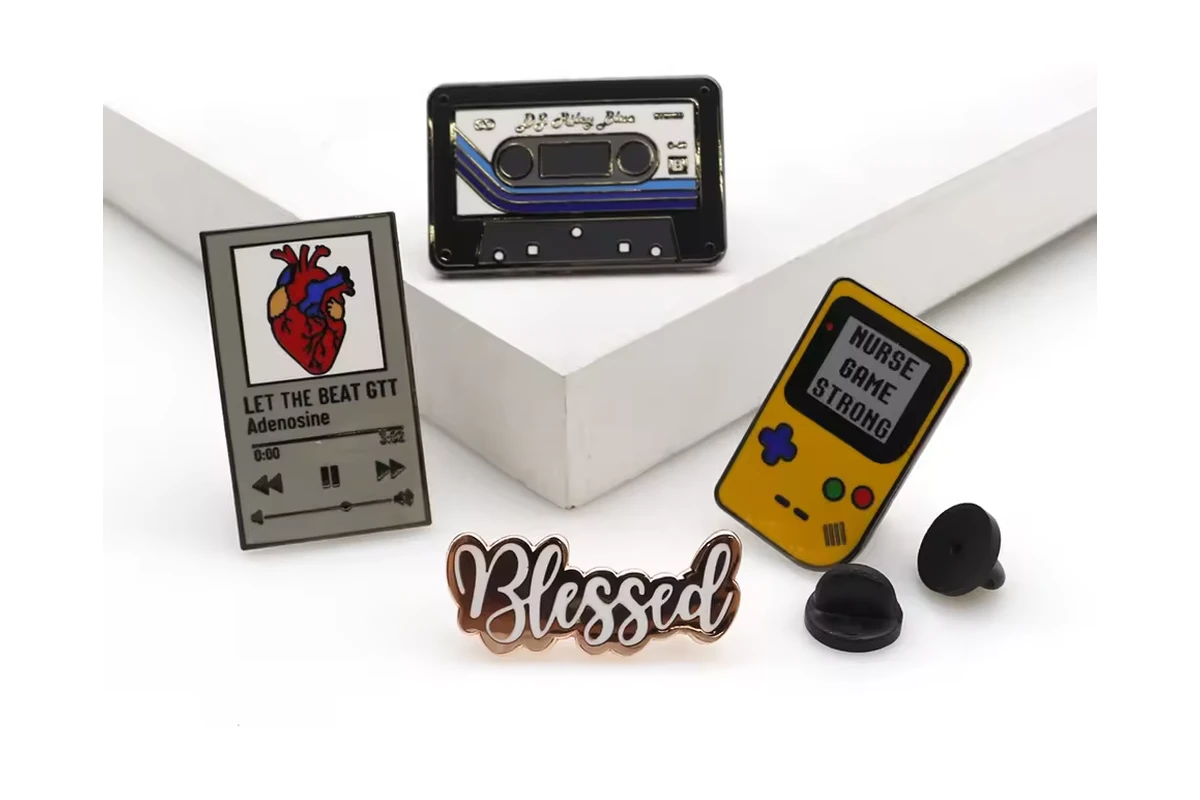Cassette-player, handheld-game and word-shaped pins beside two black rubber clutches.