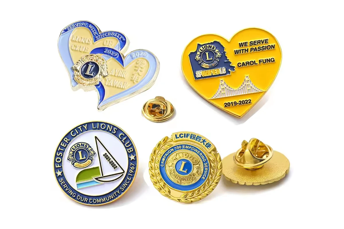 Lions Club recognition pins in heart and circular shapes with blue, gold and yellow details.