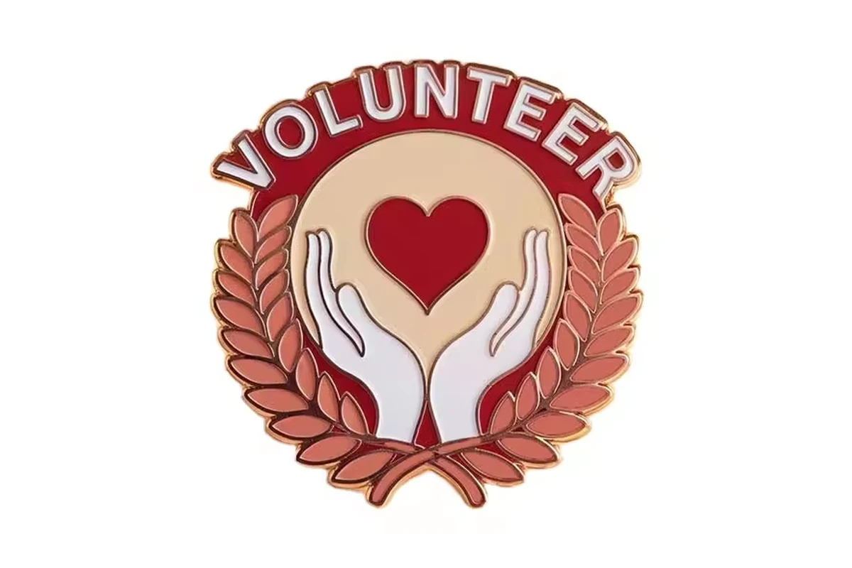 Volunteer recognition pin with a red heart, cupped hands and laurel wreath.