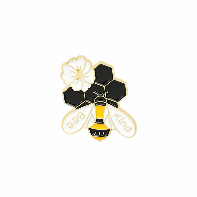 Bee pin with a white flower, black honeycomb and the words Bee Kind on its wings.