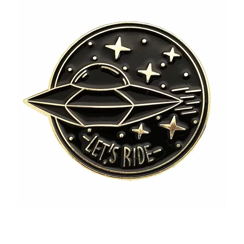 Black circular UFO pin with gold-tone outlines, a flying saucer, stars and LET’S RIDE lettering on a white background.