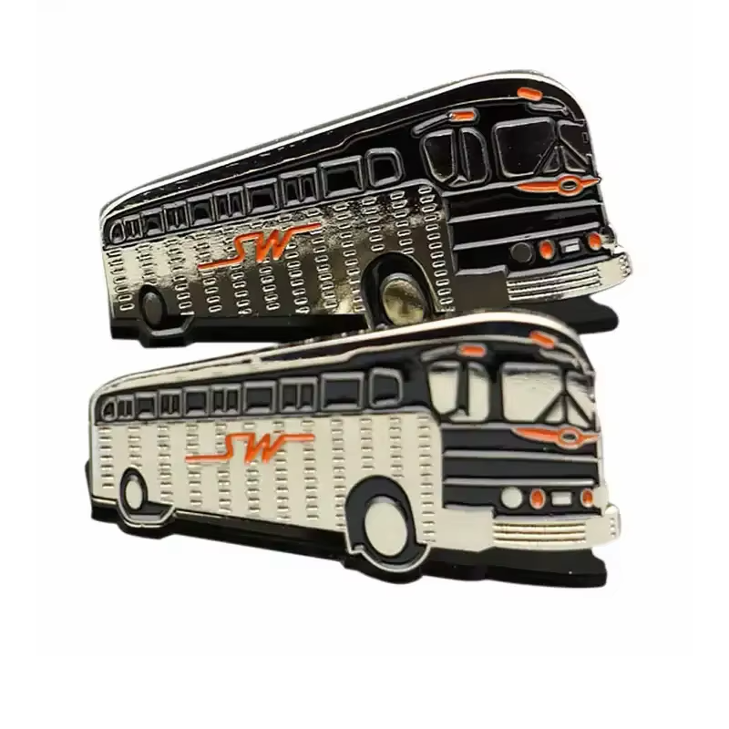 Two black and silver-tone coach bus pins with orange accents, detailed windows and wheels on a white background.