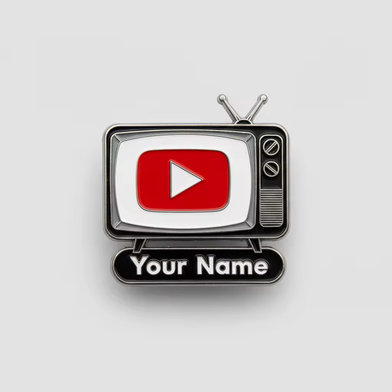 Black and silver-tone retro television pin with antennas, two control knobs, a red play icon on a white screen and Your Name lettering on its base against a pale gray background.