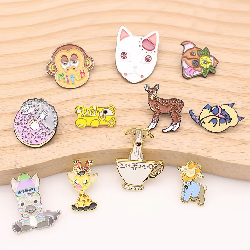 Assorted cartoon animal pins, including cats, dogs, a monkey, a deer and a giraffe, displayed on a wooden board.