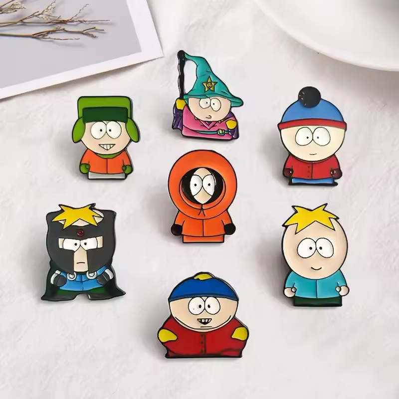 Seven cartoon character pins in winter hats, an orange hood and fantasy costumes, arranged on a white surface.