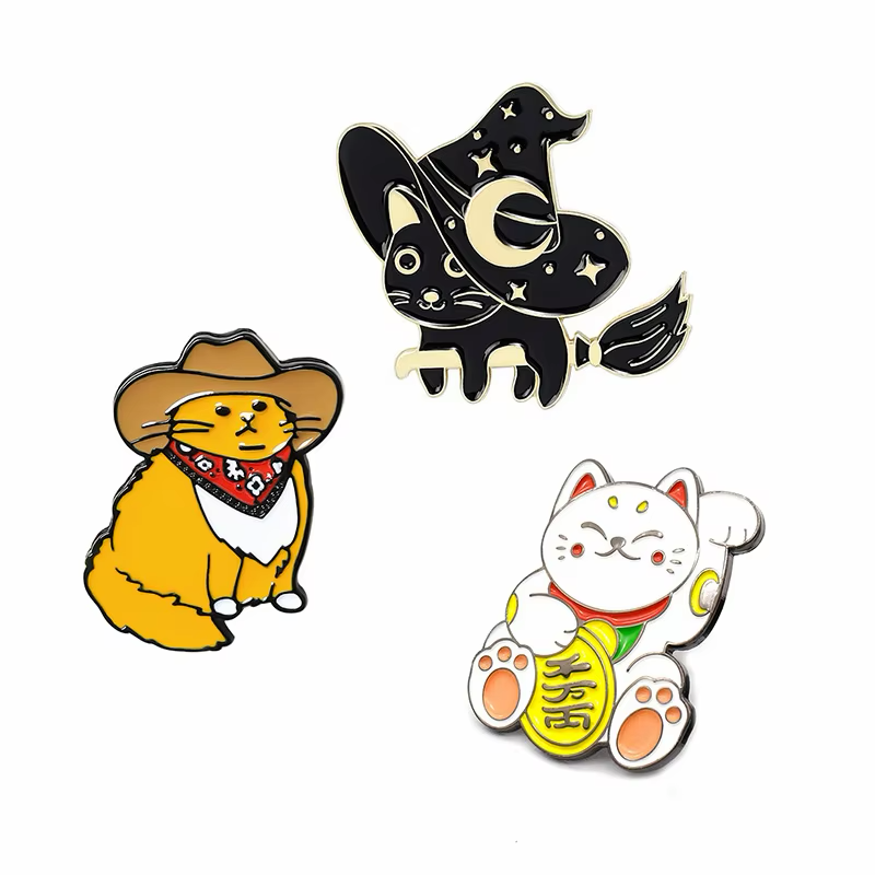 Cowboy cat, witch cat and white lucky cat pins displayed together.