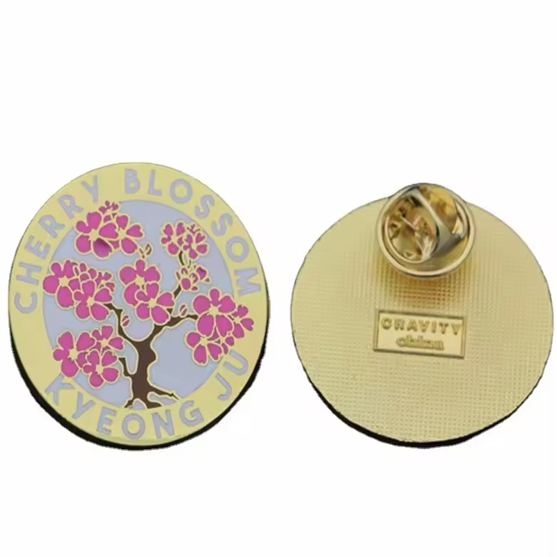 Round cherry blossom pin marked Cherry Blossom and Kyeong Ju, shown with its textured gold-colored back and butterfly clutch.