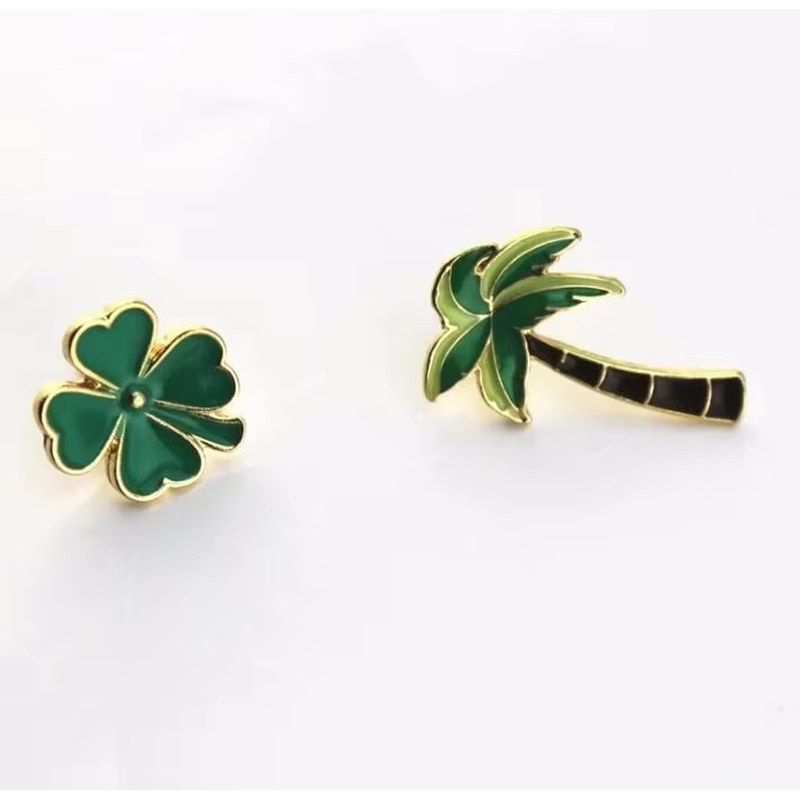 Green clover and palm tree pins with gold-colored borders.
