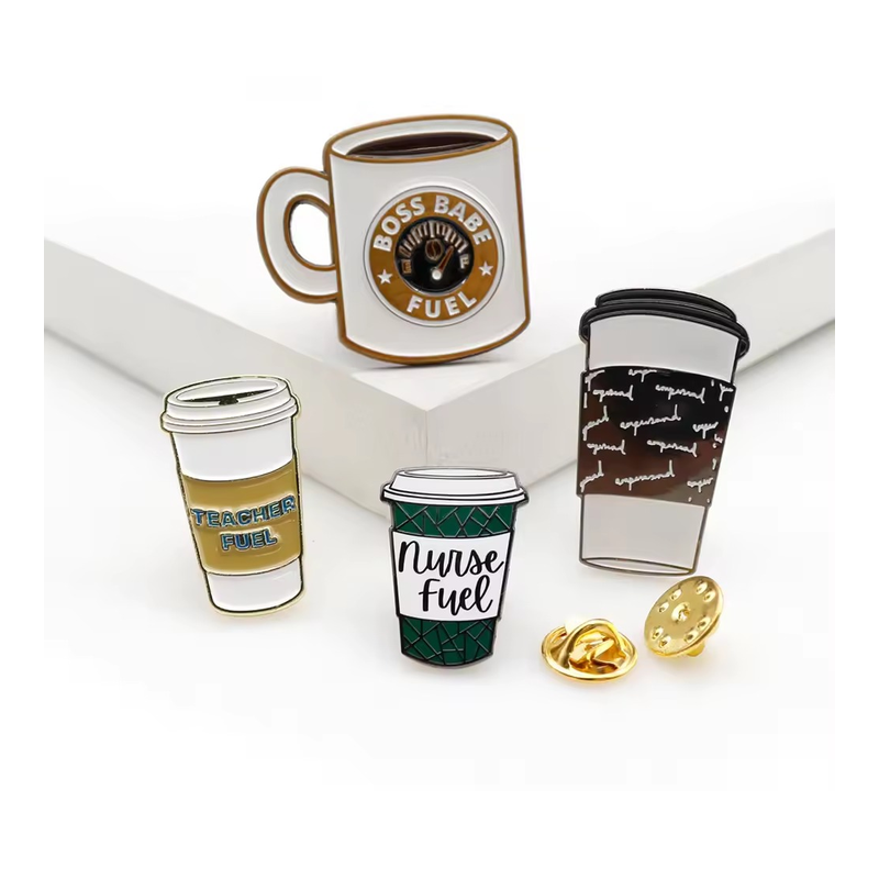 Four coffee cup pins on white display blocks, including a BOSS BABE FUEL mug, TEACHER FUEL and Nurse Fuel takeaway cups, with gold-tone butterfly clutches.
