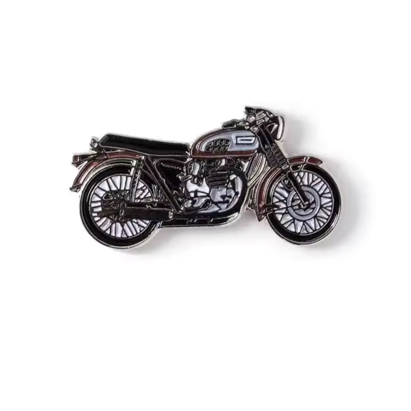 Dark vintage road motorcycle pin with a long black seat, spoked wheels and silver-tone engine details, photographed on a white background.