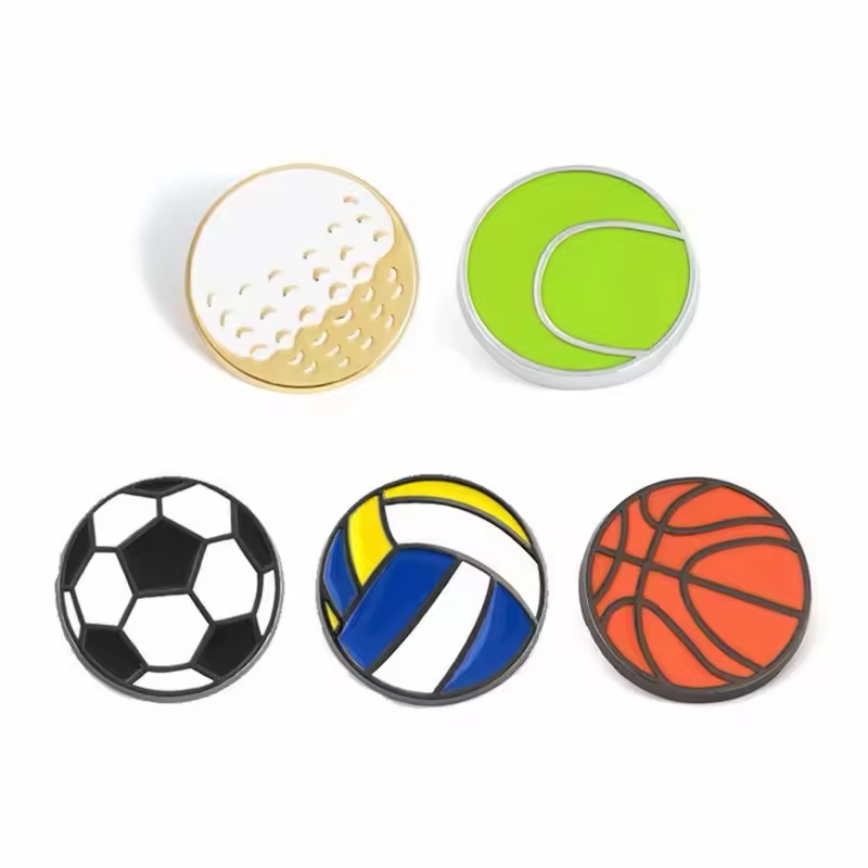 Five sports ball pins showing a golf ball, green tennis ball, black and white soccer ball, blue-yellow-white volleyball and orange basketball.