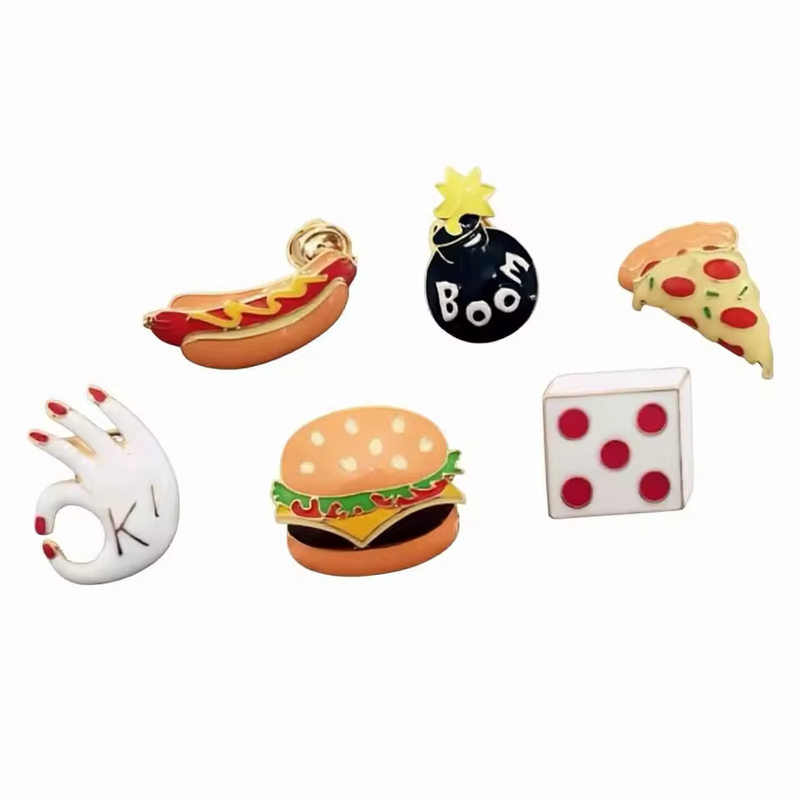Six novelty pins: a hot dog, a cartoon bomb marked Boom, a pizza slice, an OK hand, a burger and a die.