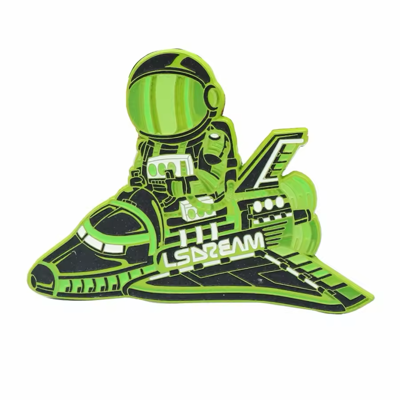 Green and black astronaut pin riding a space shuttle with white lettering.