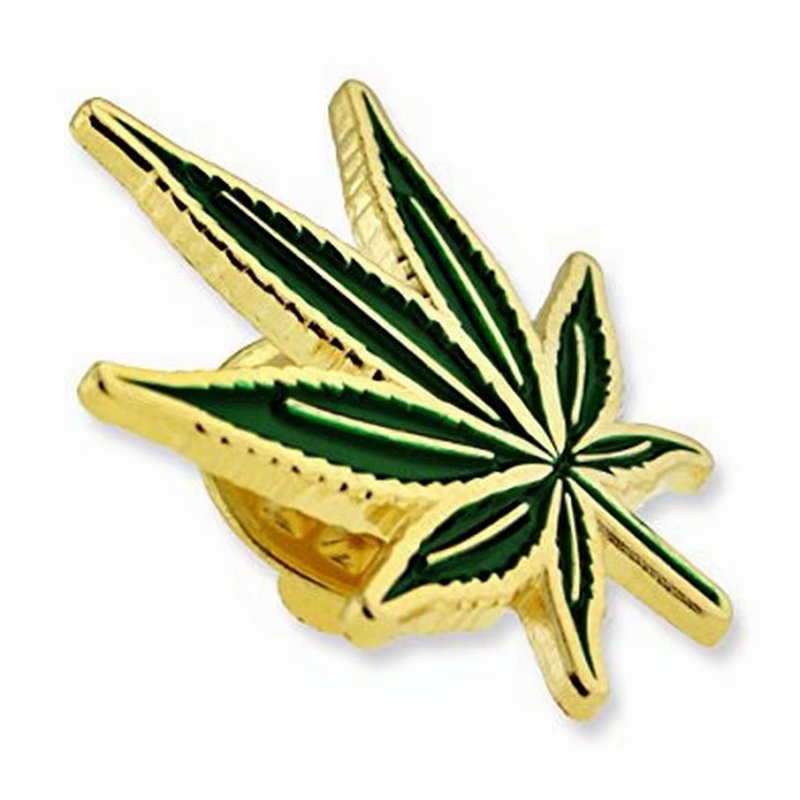 Green cannabis leaf pin with gold-colored veins and border.