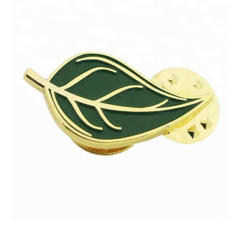 Green leaf pin with gold-colored veins and outline, displayed with a round pin clutch.