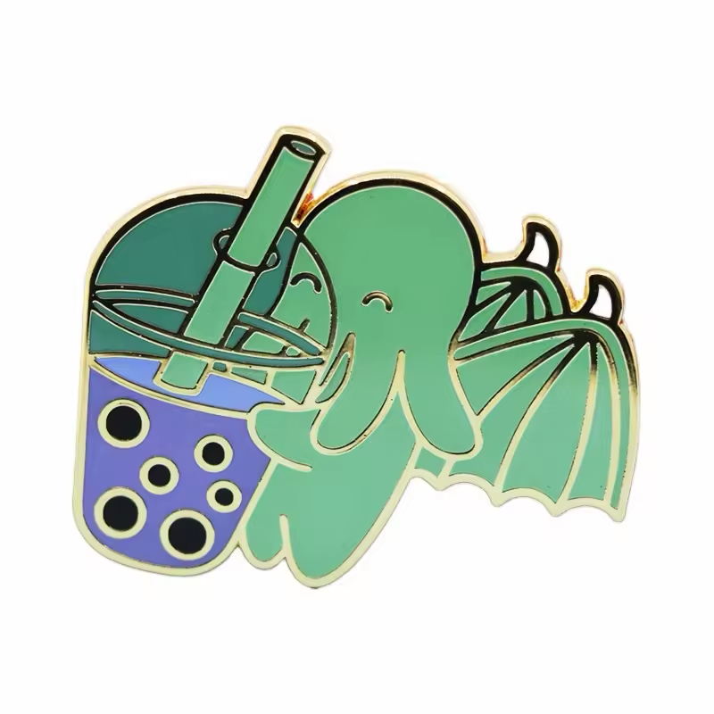 Green winged tentacled character pin holding a purple bubble tea cup with black pearls and a green straw, with gold-tone outlines on a white background.