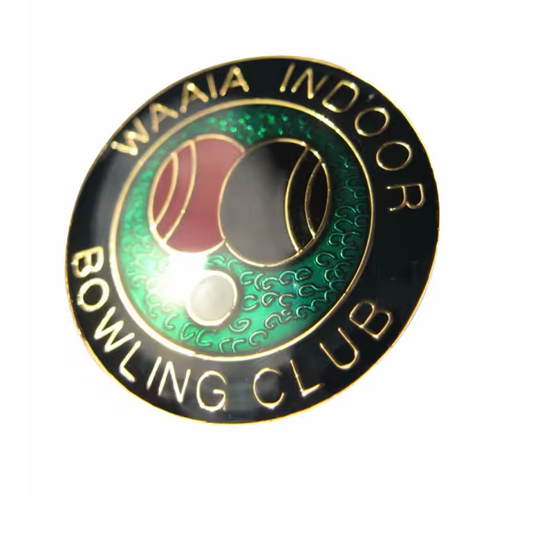 Indoor bowling club pin with a black circular border, green center, red and black bowls, a small white ball and gold-tone lettering.