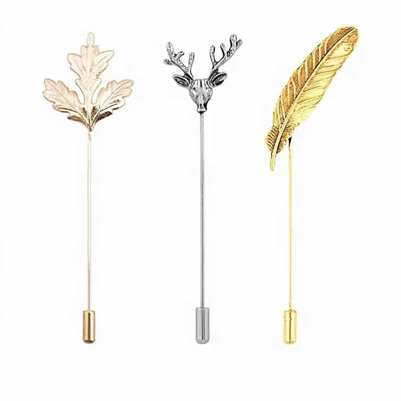 Three stick pins with leaf, stag head and feather tops and capped stems.