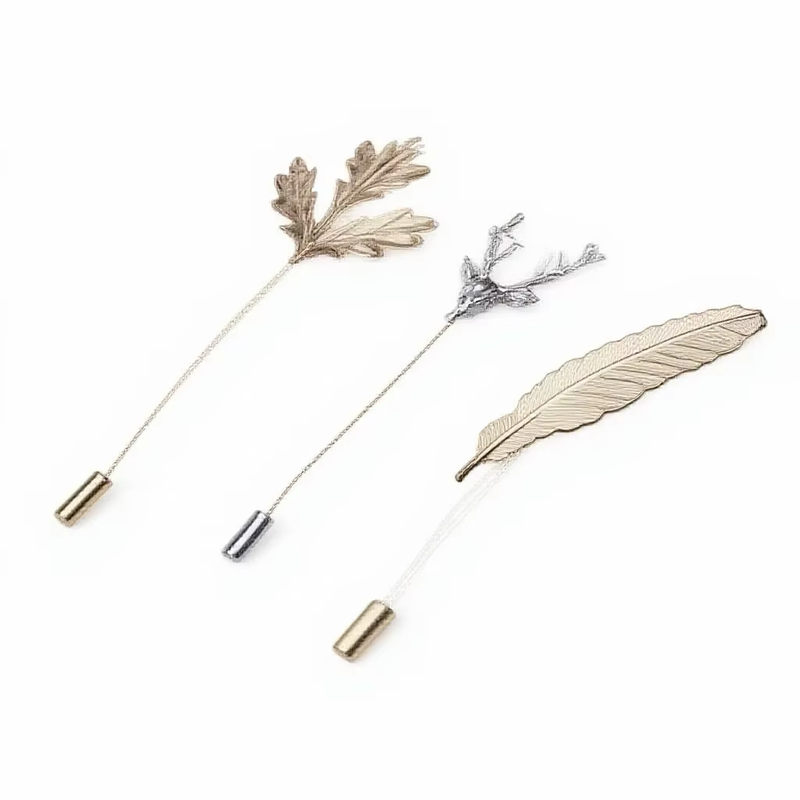 Leaf, stag head and feather stick pins arranged diagonally on a white background.