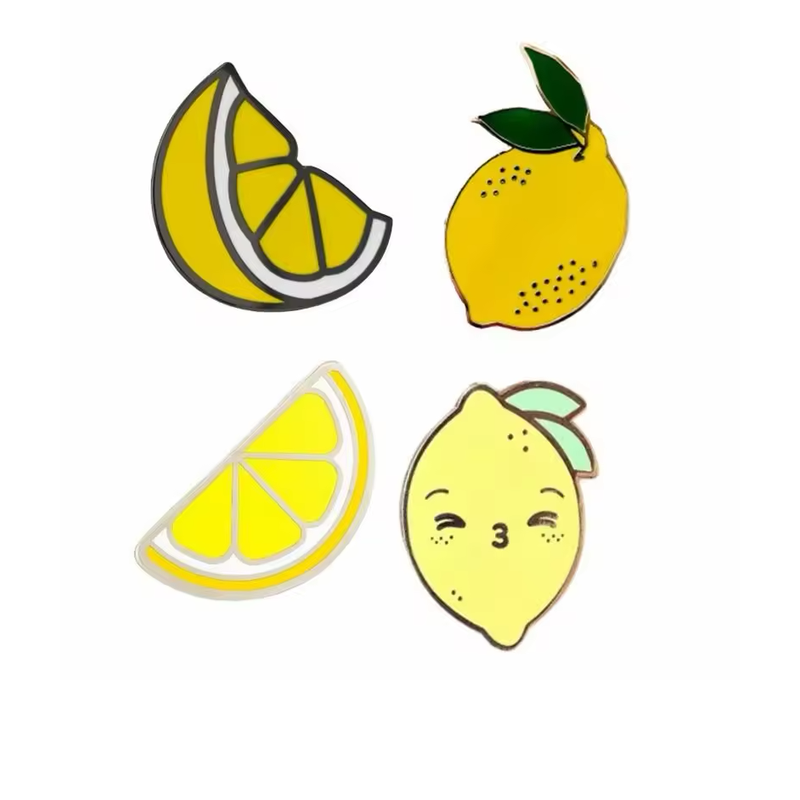 Four lemon pins showing two yellow slice designs, a whole lemon with dark green leaves and a pale yellow lemon with a smiling face.