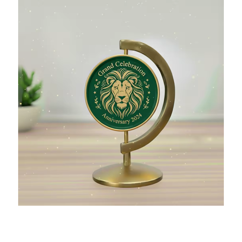 Green lion medallion in a gold-tone curved tabletop stand, with Grand Celebration and Anniversary 2024 lettering on a wooden surface.