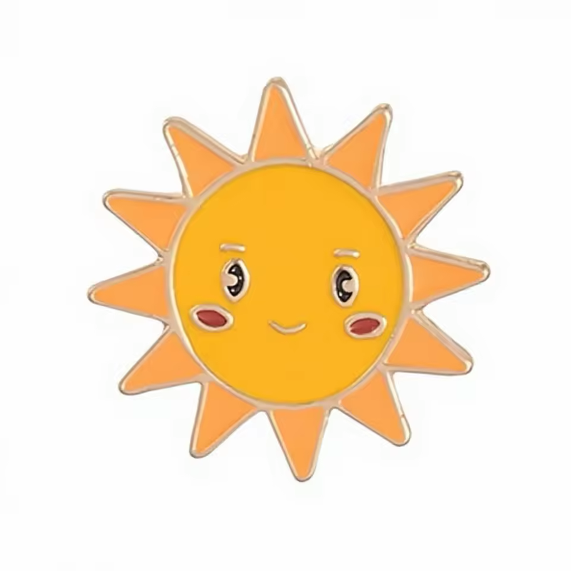 Smiling sun pin with a golden-yellow face, orange triangular rays, red cheeks, expressive eyes and gold-tone outlines on a white background.