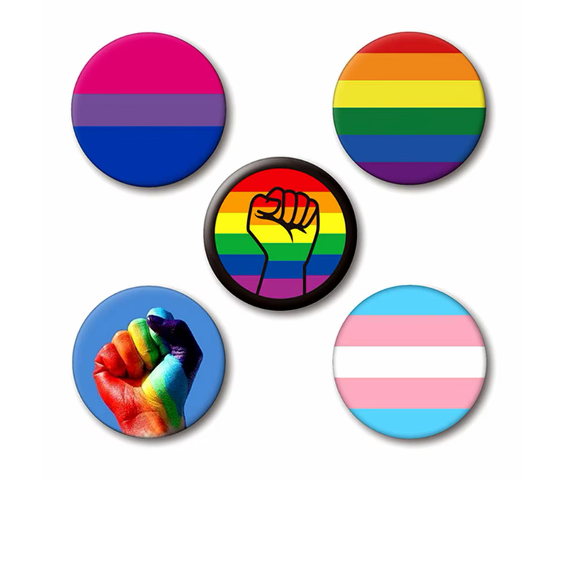 Five round Pride button badges featuring bisexual, rainbow and transgender flags, a raised fist over rainbow stripes and a rainbow-painted fist on blue, on a white background.