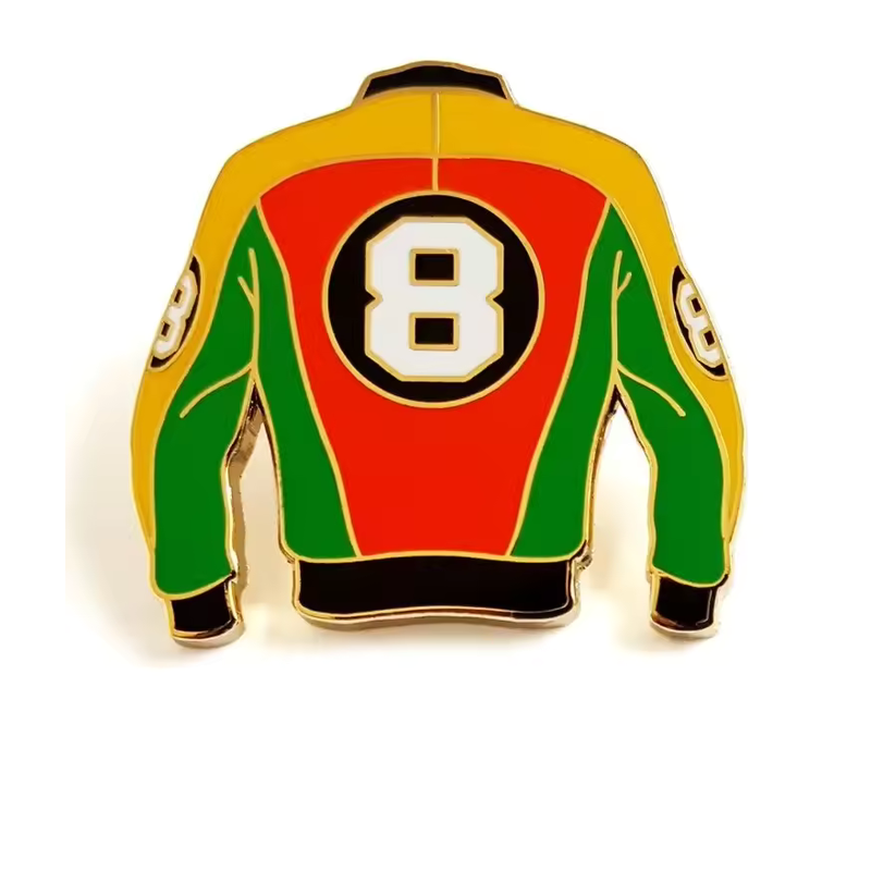 Jacket-shaped pin viewed from the back with red, yellow and green panels, black cuffs and a large white number 8 in a black circle on a white background.