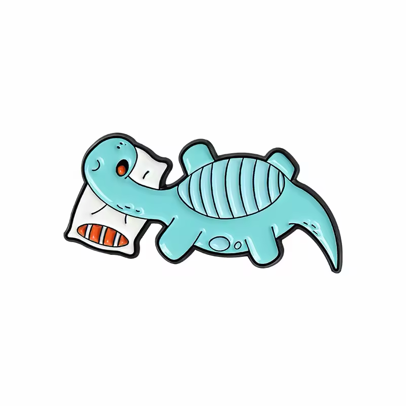 Turquoise cartoon dinosaur pin resting on a white pillow.