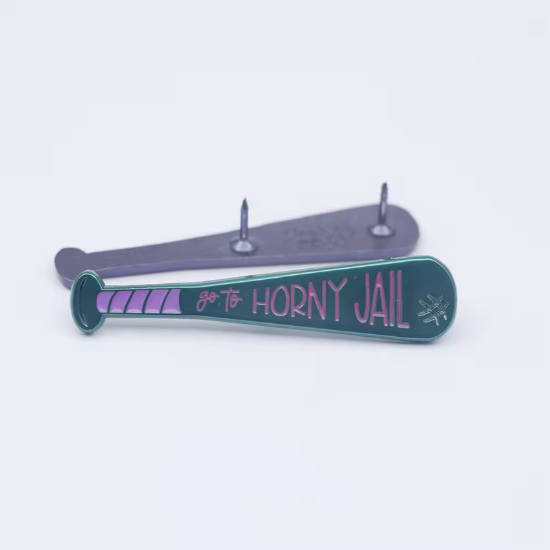 Teal baseball bat pin with purple lettering reading go to HORNY JAIL, shown with its two-post reverse on a pale background.