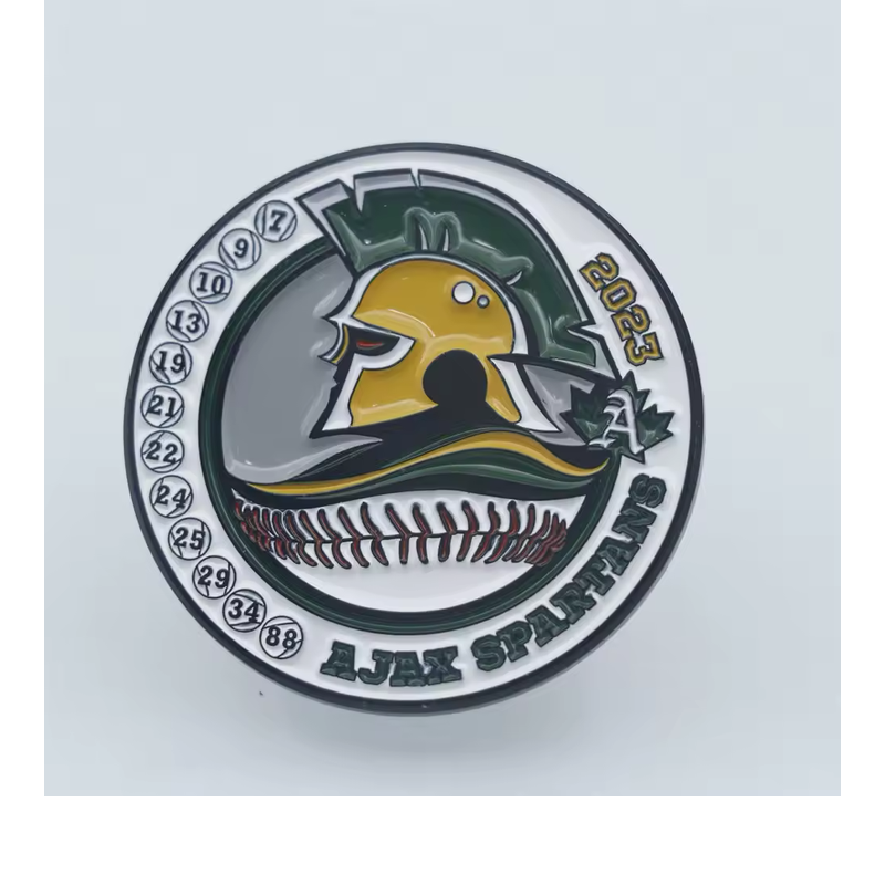 Round baseball team pin with a gold-colored Spartan helmet, player numbers, Ajax Spartans lettering and 2023.