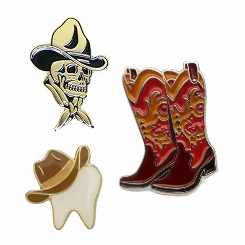 Western-themed pins showing a skull in a cowboy hat and bandana, red and orange cowboy boots, and a white tooth wearing a brown cowboy hat on a white background.