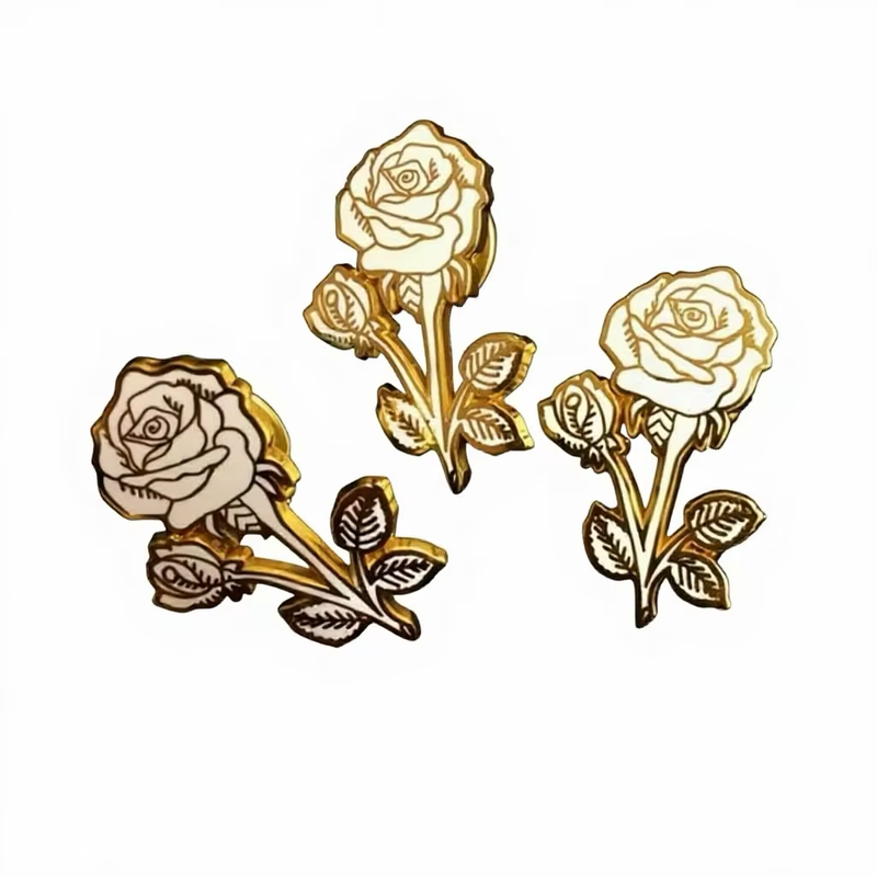 Three white rose pins with gold-colored stems, leaves and borders.