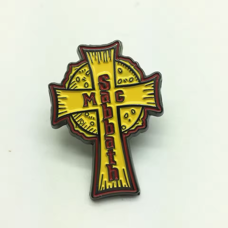 Yellow cross-shaped pin over a circular design with red Mac Sabbath lettering, black outlines and a red border on a pale background.