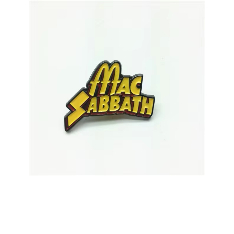 Yellow Mac Sabbath lettering pin with black outlines and red shadow details, photographed on a pale background.
