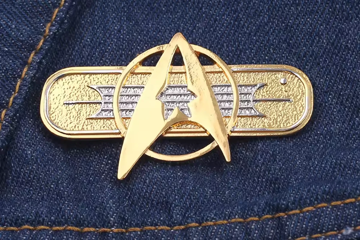 A gold-colored and silver-colored emblem pin on dark blue denim.