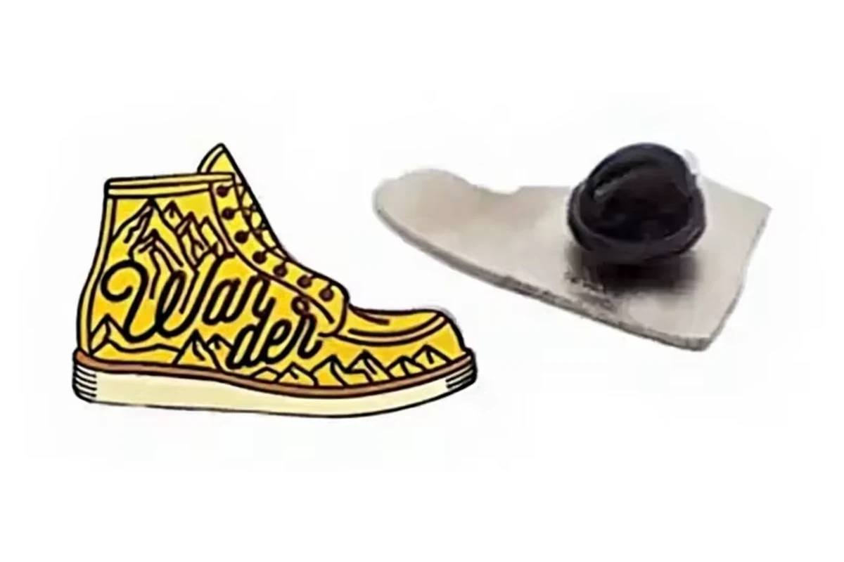 A small yellow shoe-shaped pin with its silver reverse and black rubber clutch.